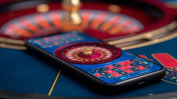 একজন পুরুষ তার ল্যাপটপে জয়ের মুহূর্ত উদযাপন করছেন, চারপাশে ভাসছে গেমিং আইকন—যা BAJI2000 গেমসের উত্তেজনাকে প্রকাশ করে।